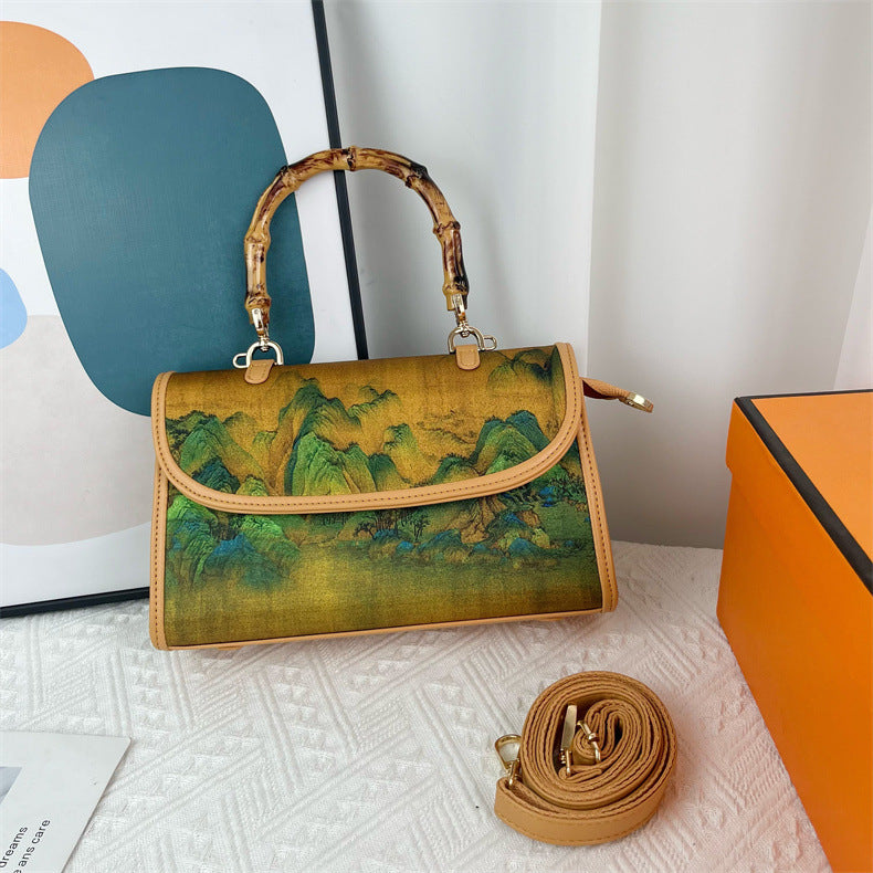 Handbag with green abstract design and bamboo handle on a white surface