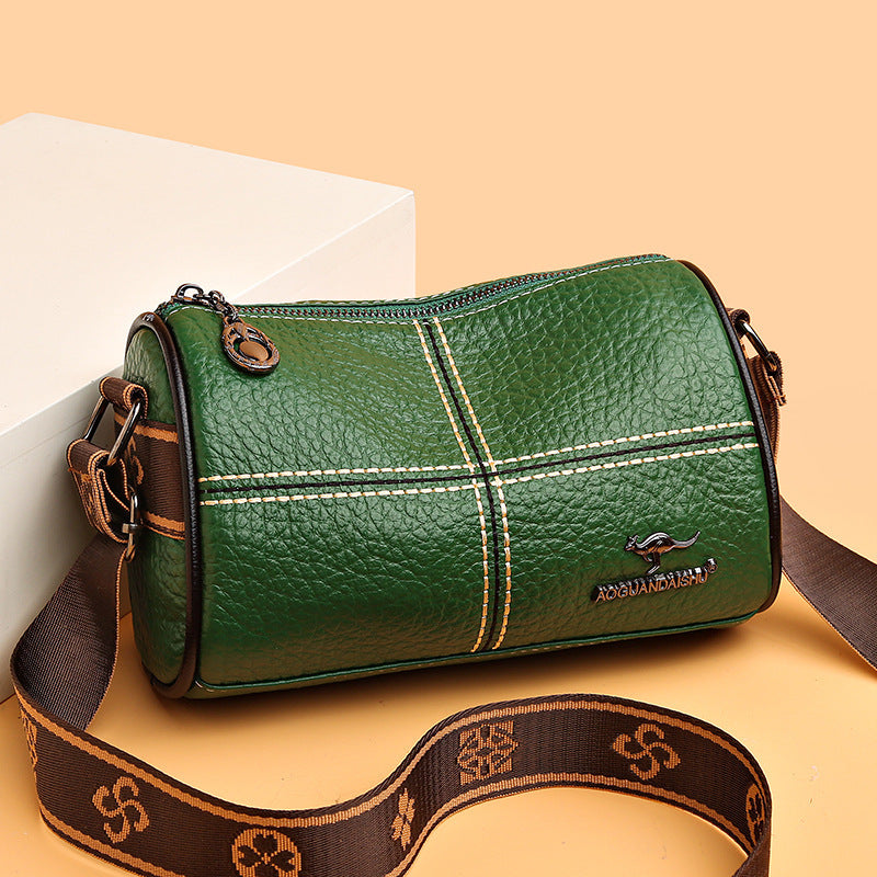 Green leather handbag with brown strap on a beige background