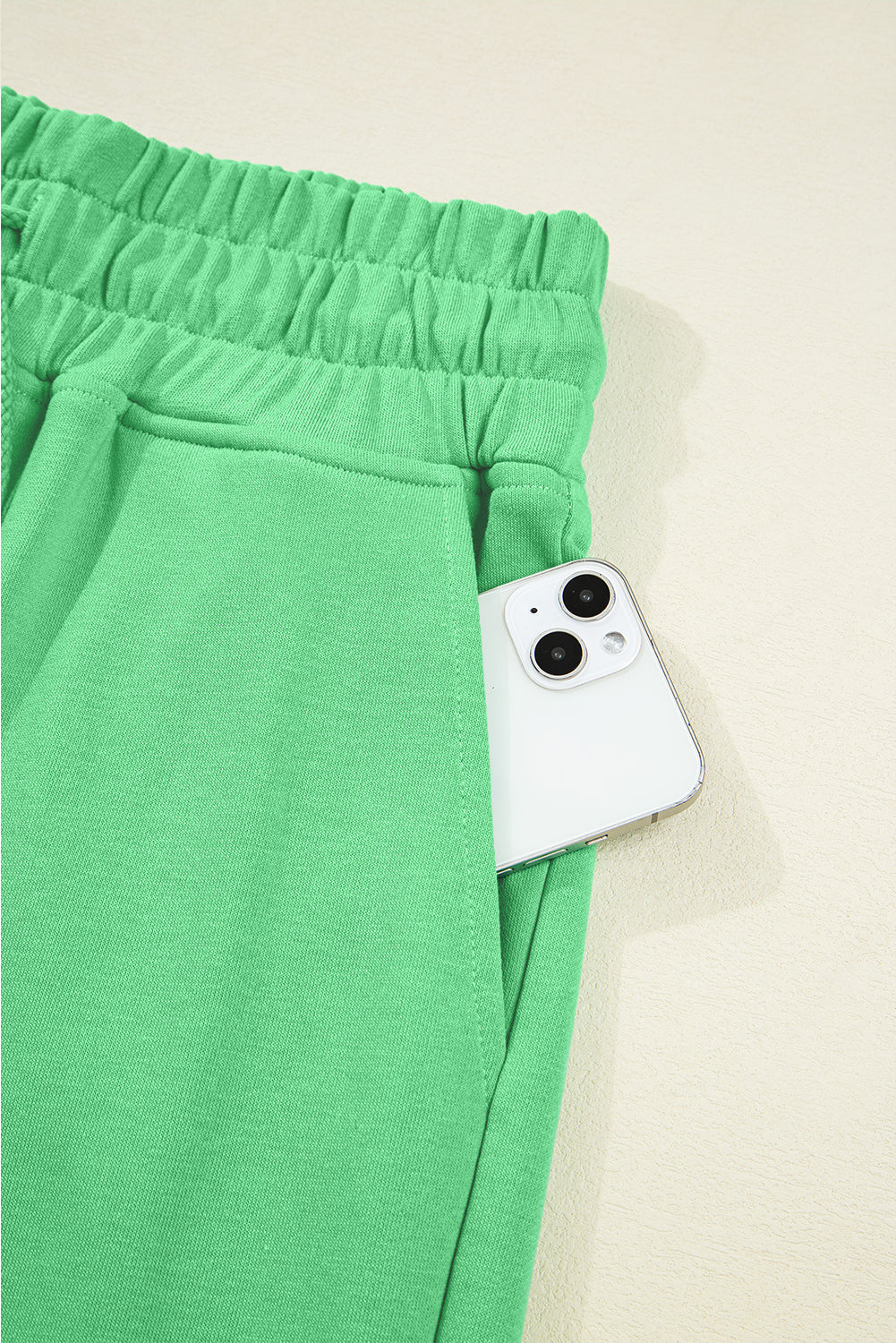 Green pants with a white phone pocket on a beige background