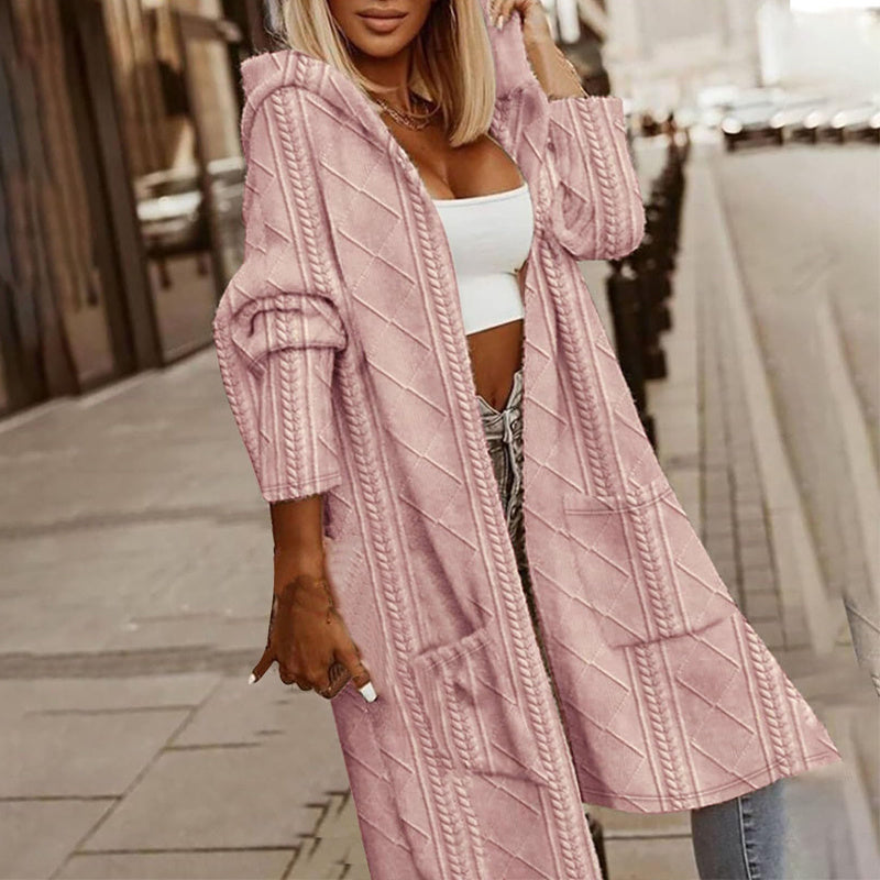 Woman wearing a pink textured cardigan over a white top and jeans on a city street.