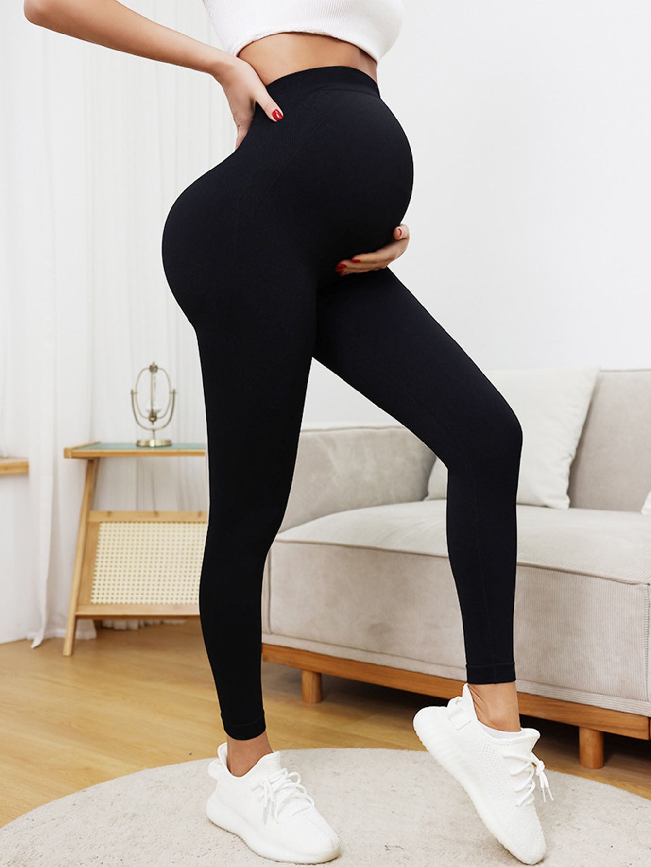 Person wearing black leggings and white sneakers in a living room setting