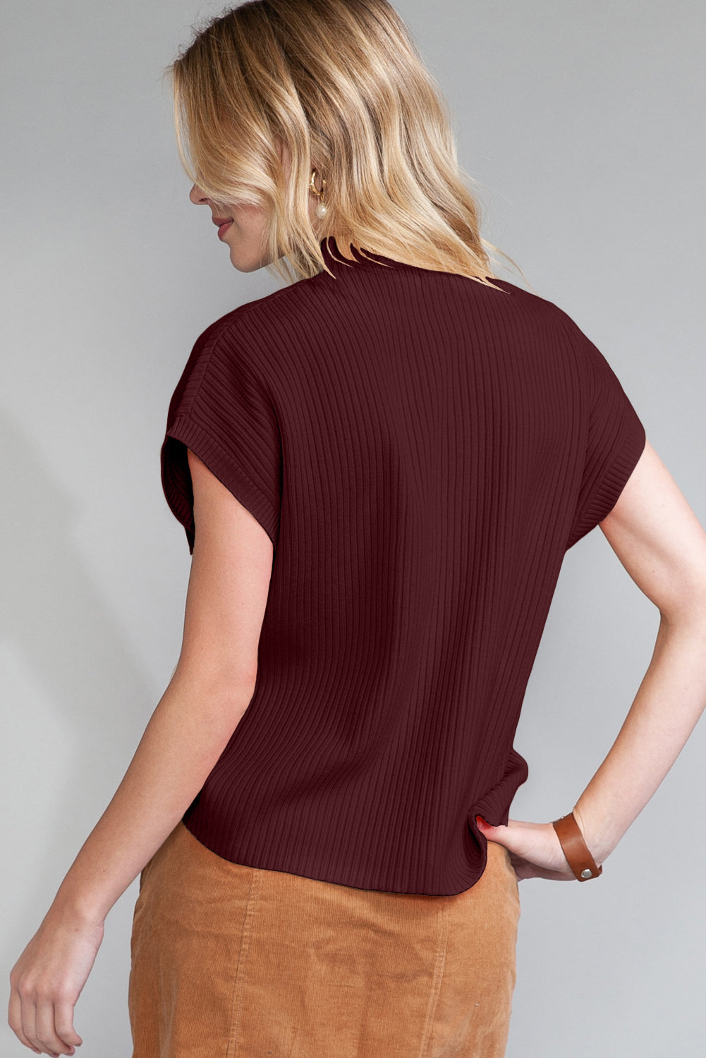 Woman wearing a maroon ribbed t-shirt against a gray background