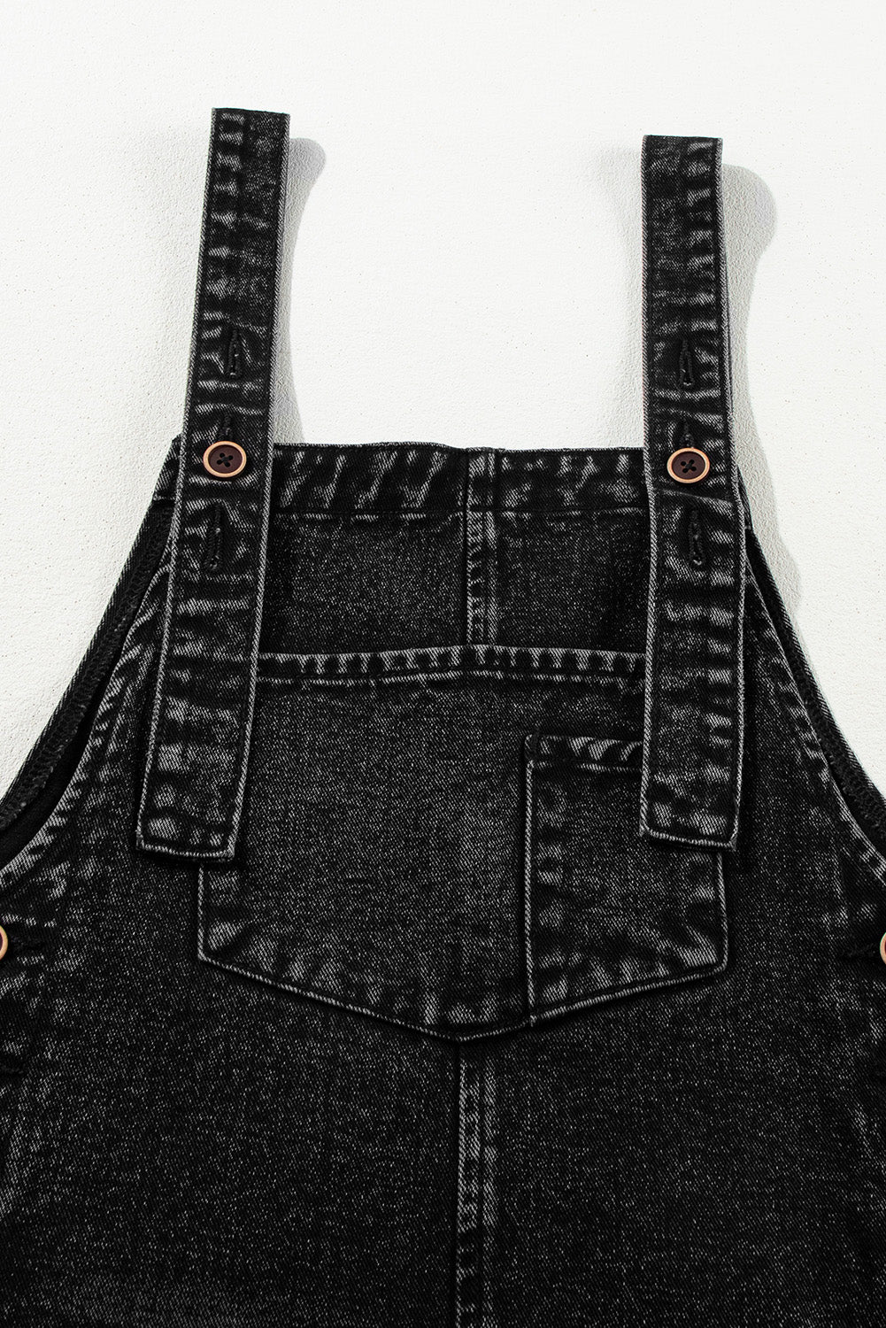 Black denim overalls on a white background