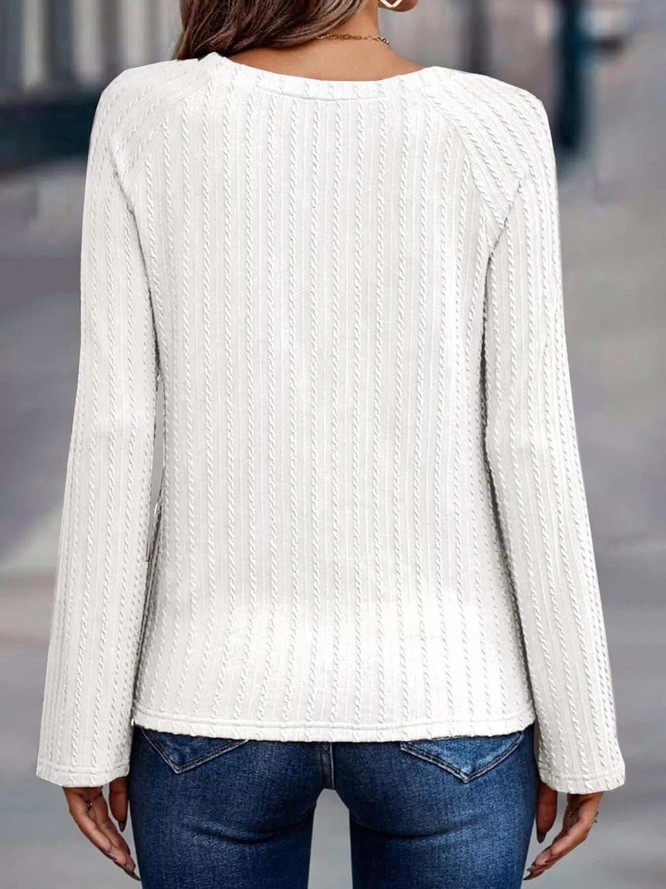 White ribbed sweater worn by a person with a blurred background