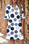 Woman wearing a polka dot blue dress with a stone wall background