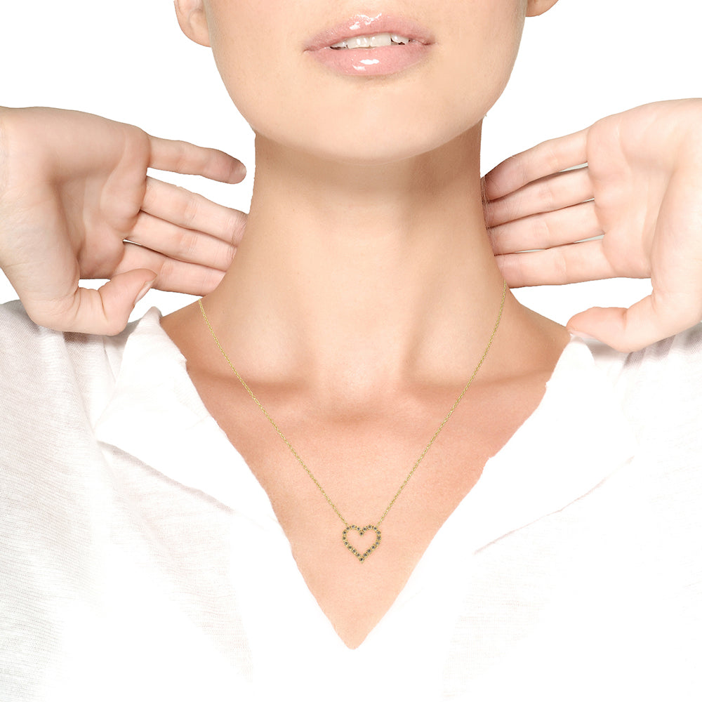 Gold heart necklace being worn on a model with a plain background