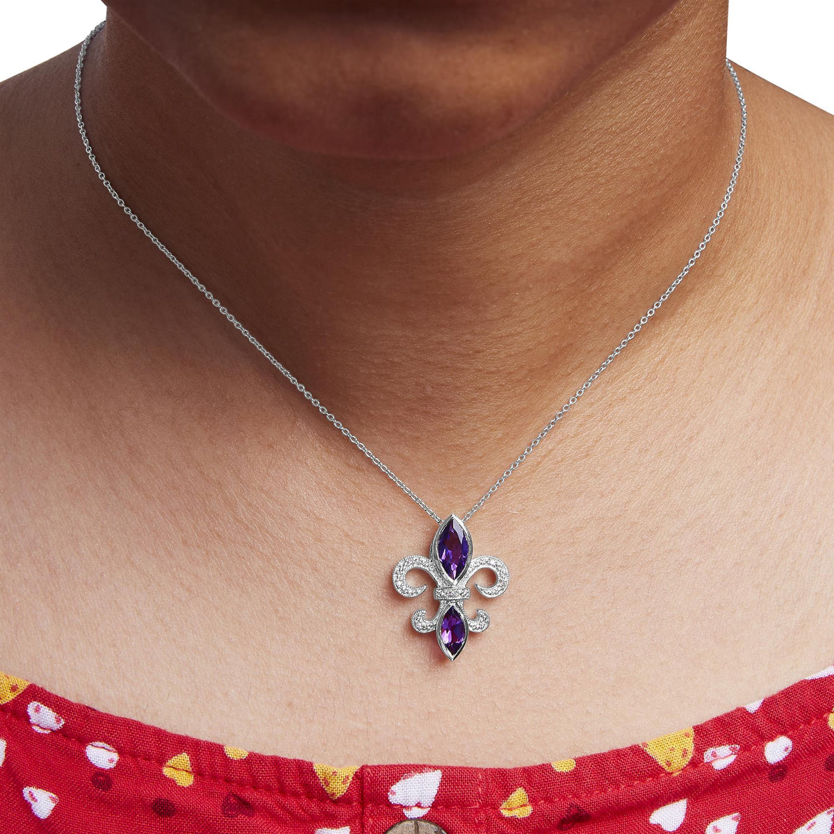 Necklace with a fleur-de-lis pendant on a person wearing a red top with white and yellow patterns.