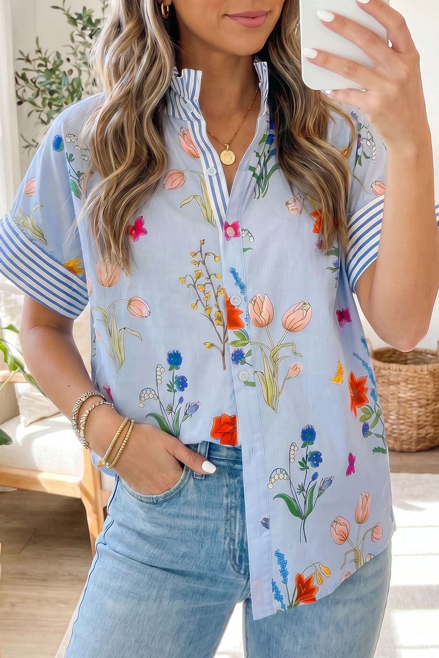 Woman wearing a floral embroidered shirt and jeans, holding a phone.
