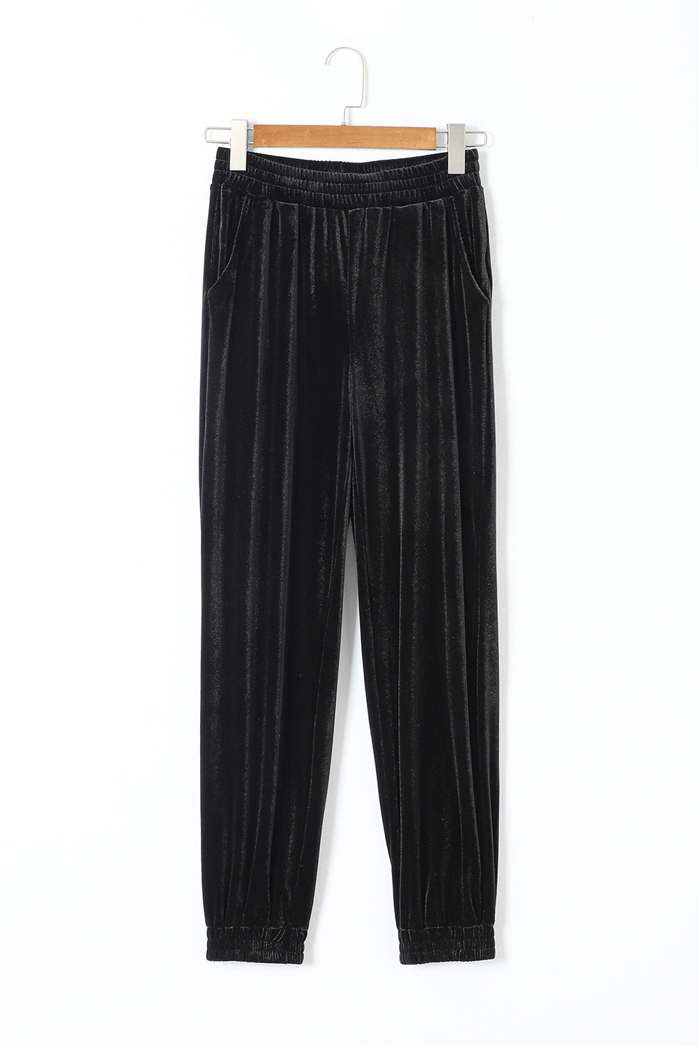 Black velvet pants on a hanger against a white background