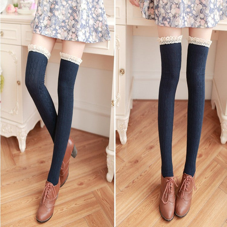 Navy blue knee-high socks with lace trim worn by a person on a wooden floor.