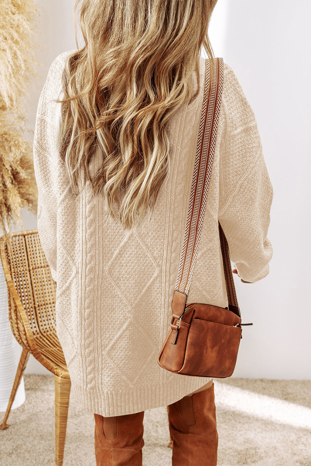 Person wearing a beige cable knit sweater dress back view