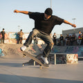 Male model wearing a Men's Short Sleeve Plaid Trim black T-Shirt on a skateboard 