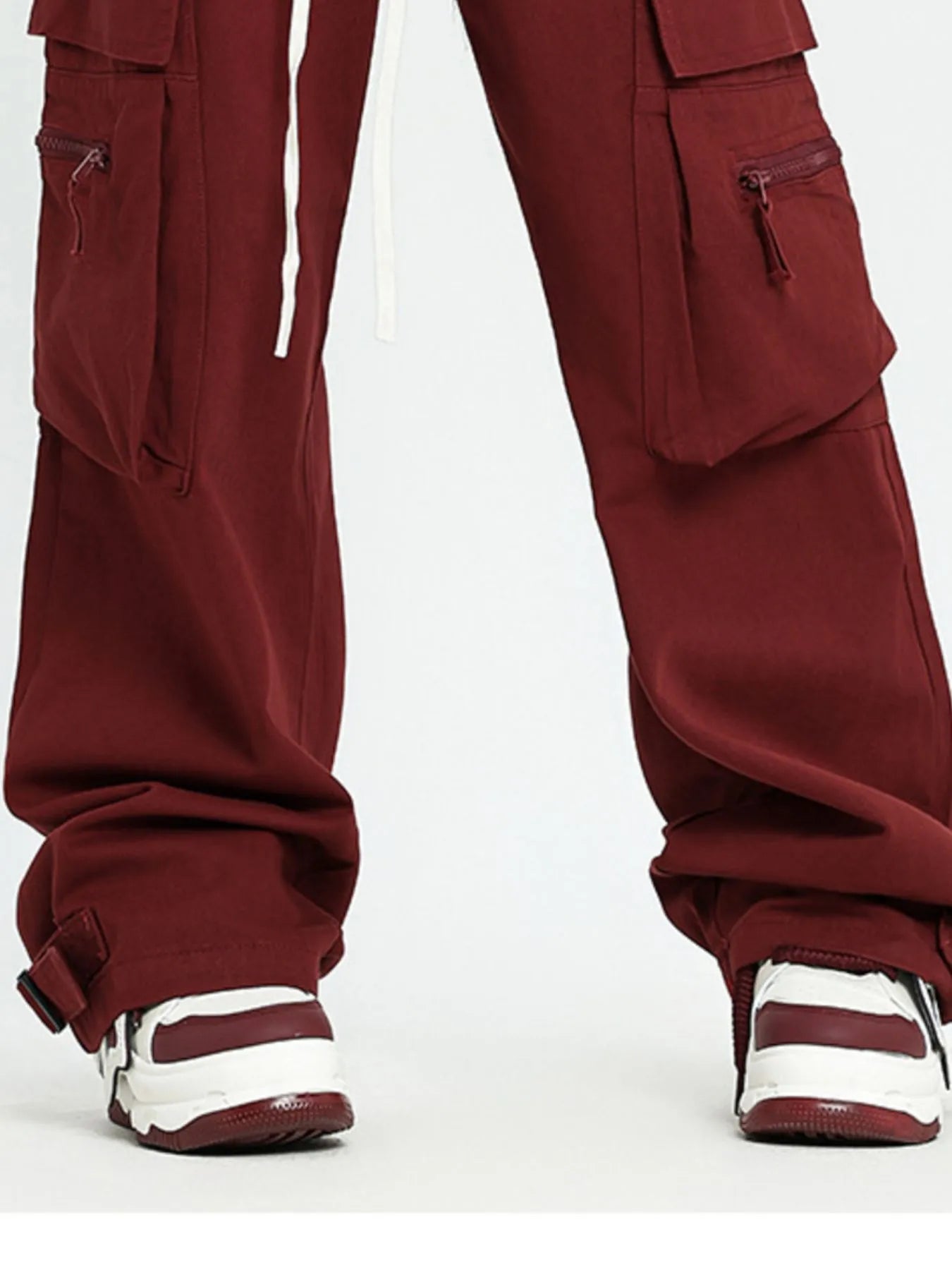 Model wearing men's Maroon wide leg cargo pants with matching white and red striped shoes 
