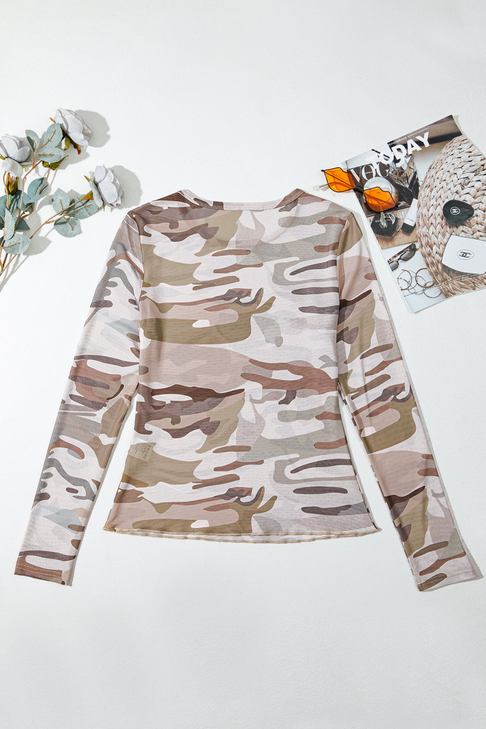 Camouflage long-sleeve shirt back on a white background with decorative elements.