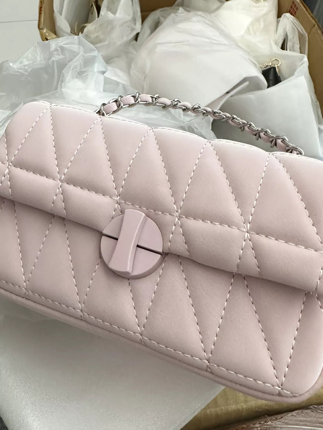Quilted handbag with a circular clasp on a white background