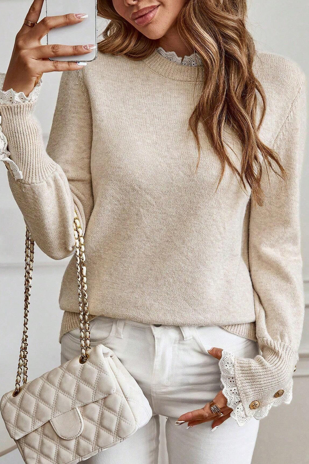 Woman wearing a beige Women's Lace Trim Buttoned Cuff Sweater with white lace cuffs and white pants.