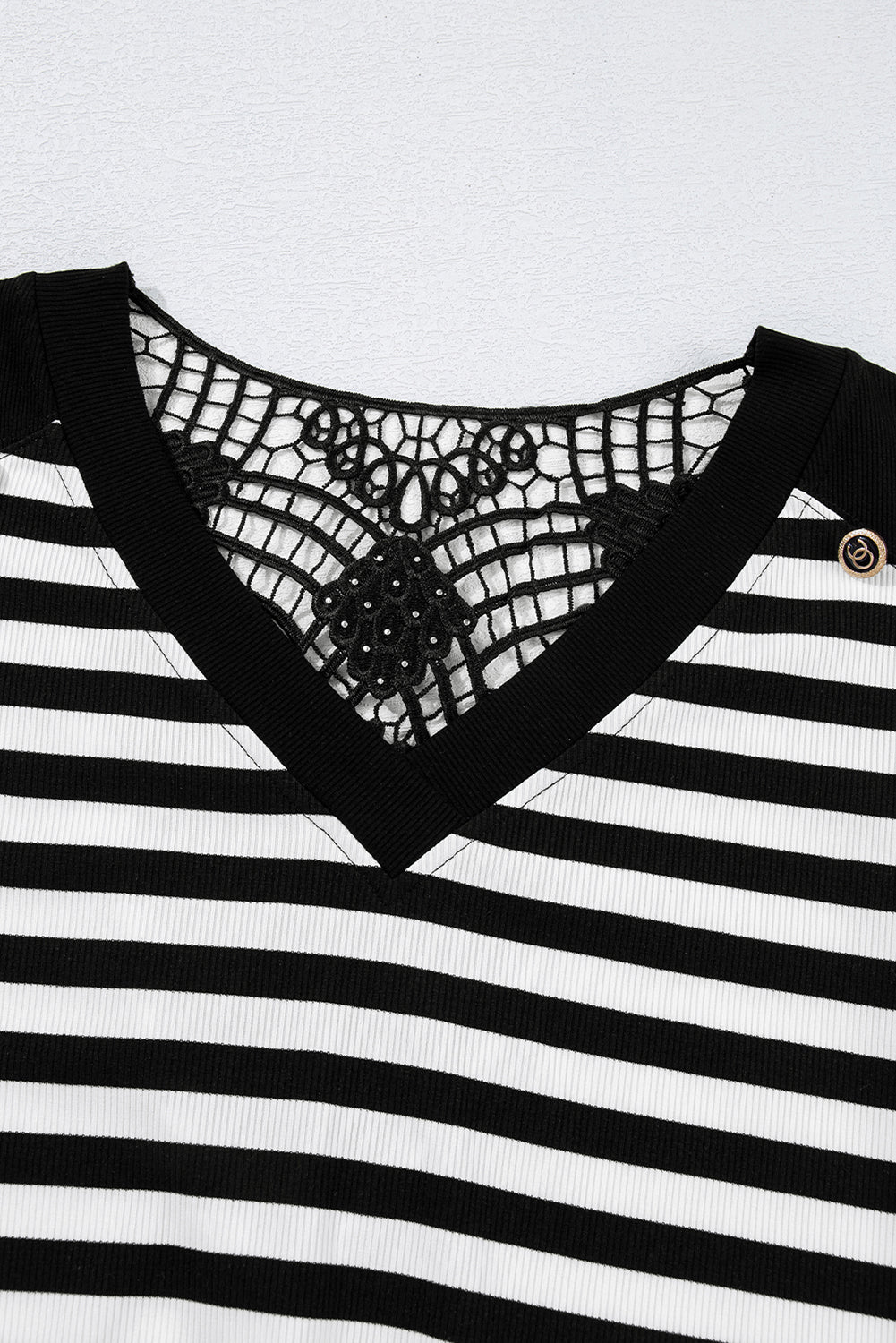 Black and white striped top with lace detailing on a light gray background