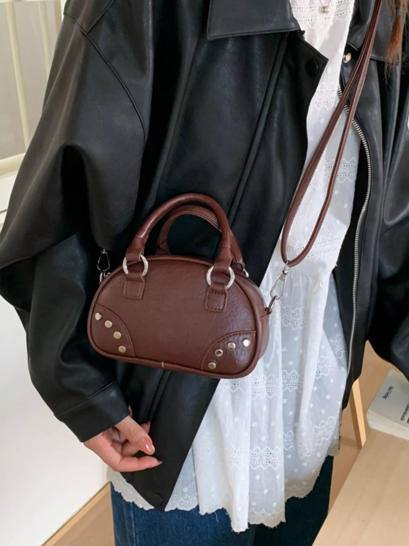 Person holding a brown handbag wearing a black leather jacket.
