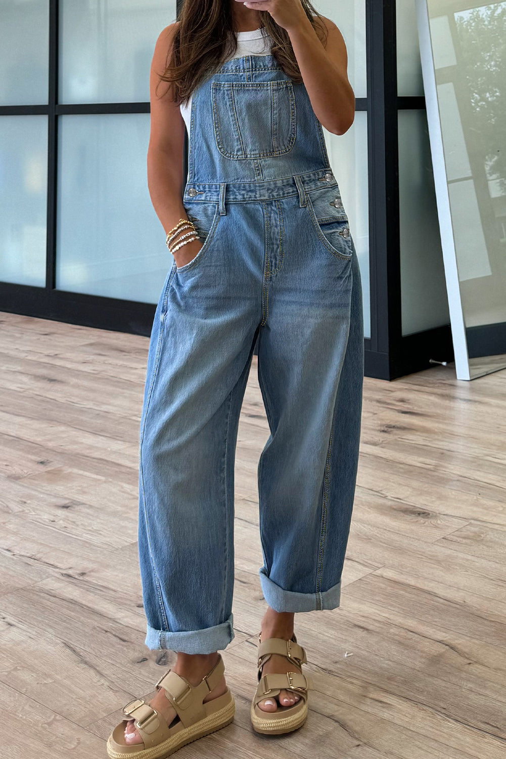 Person wearing a denim overalls standing on a wooden floor.
