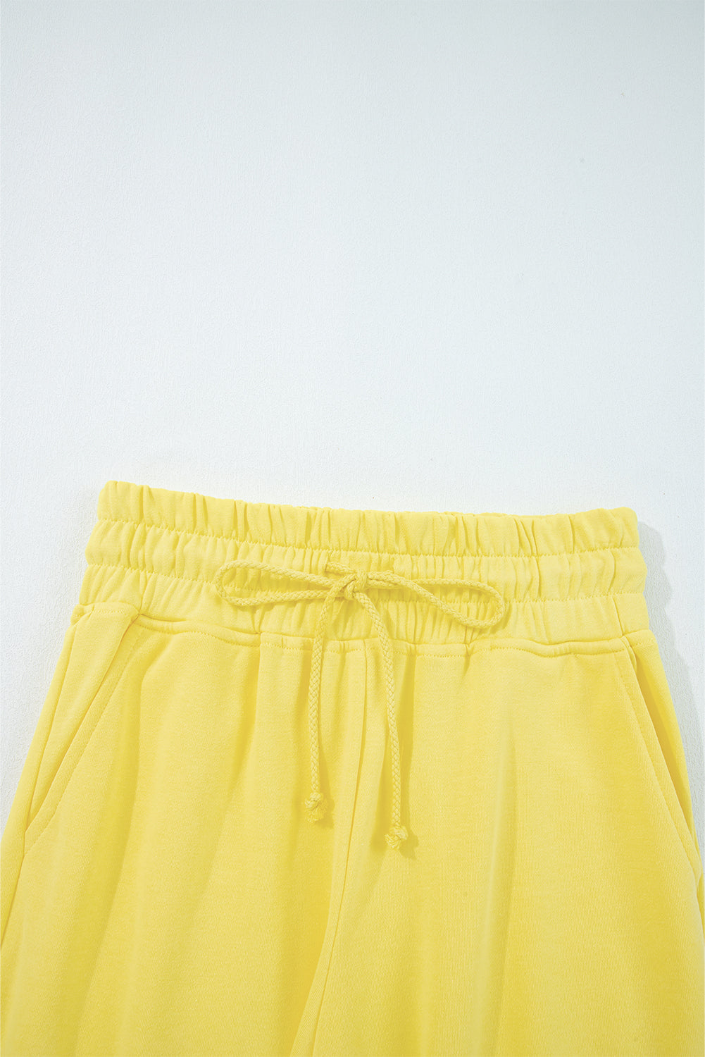Yellow pants with an elastic waistband on a light gray background
