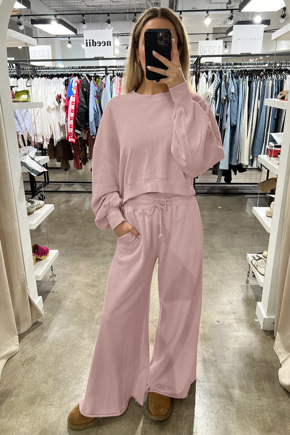 Person wearing a pink sweatshirt and pants in a clothing store.