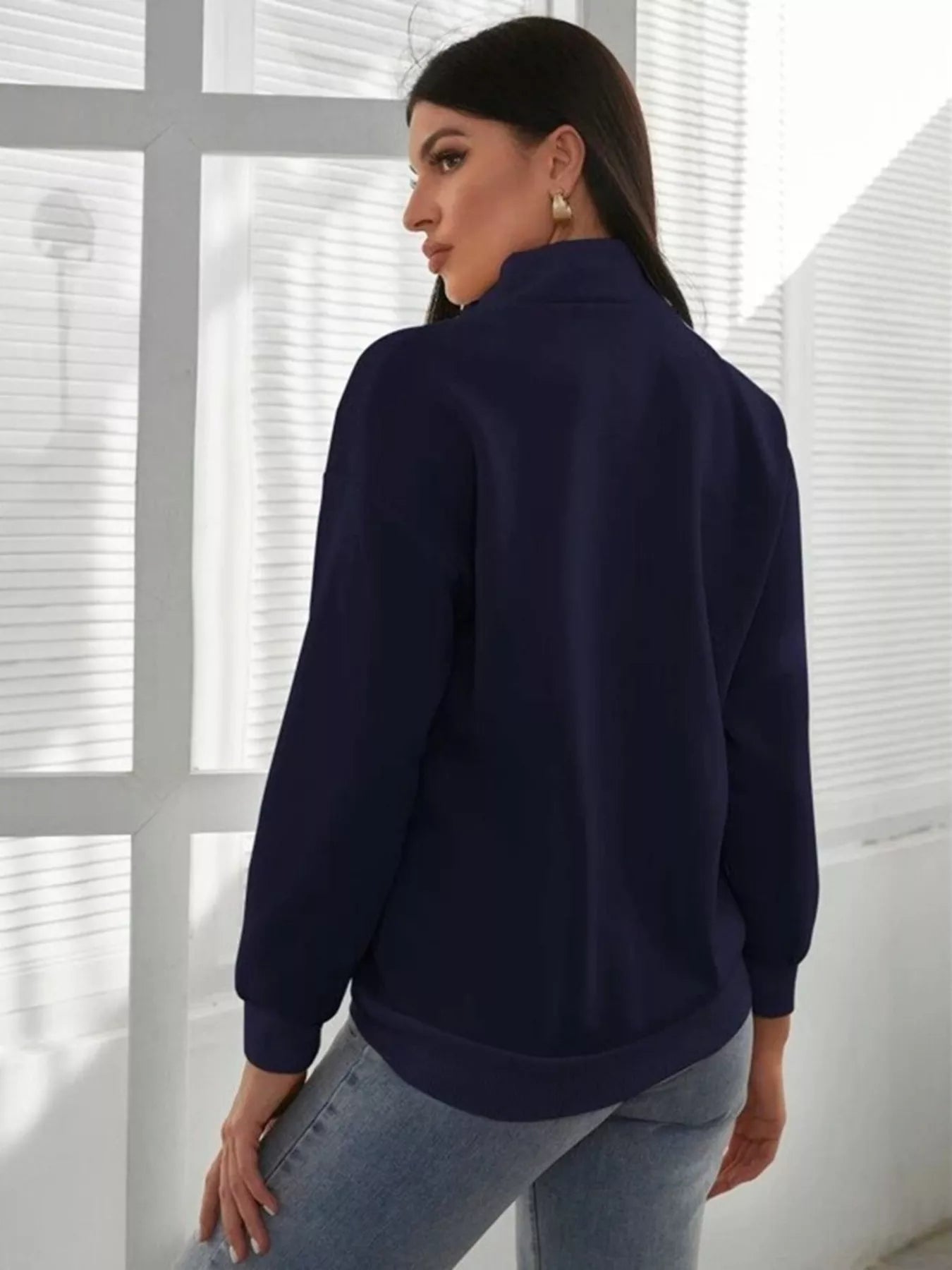 Woman wearing a navy blue sweater in a minimalistic setting