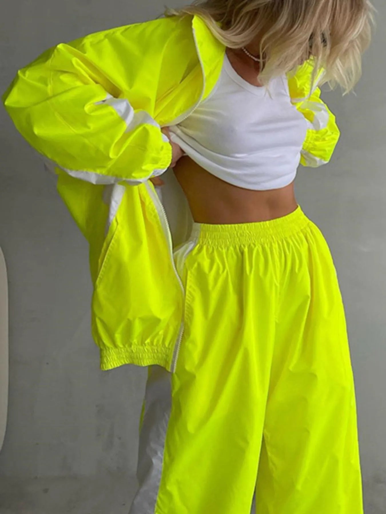 Person wearing a bright yellow outfit with a white top against a gray background