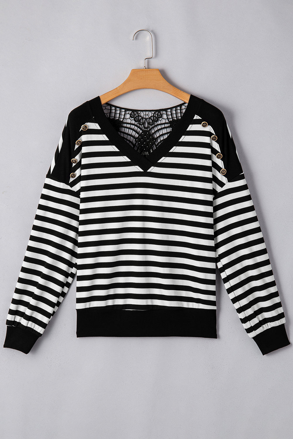 Black and white striped sweater with lace detail on a hanger against a gray background