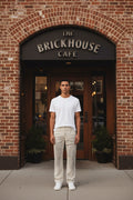 A male model in a pair of vintage washed off white jeans with a heavily distressed, ripped, and frayed design across the thighs and upper legs, 
