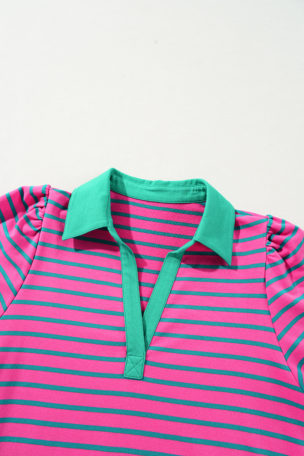 Pink and green striped polo shirt with a green collar on a light gray background