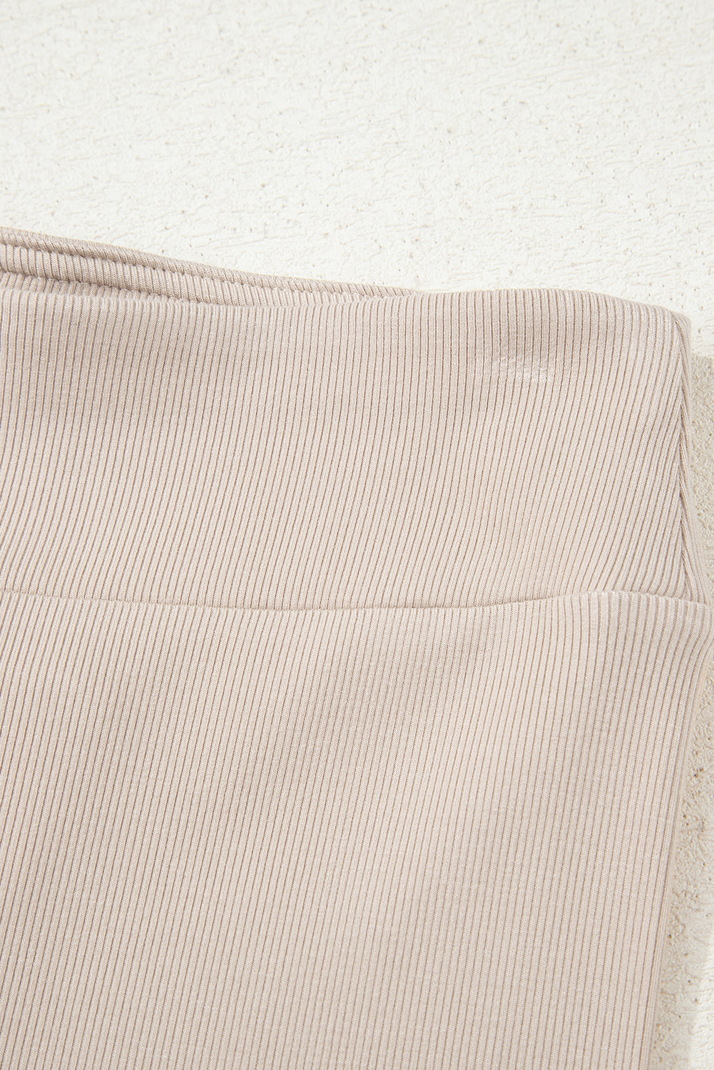 Close-up of beige ribbed fabric with a textured pattern on a white background