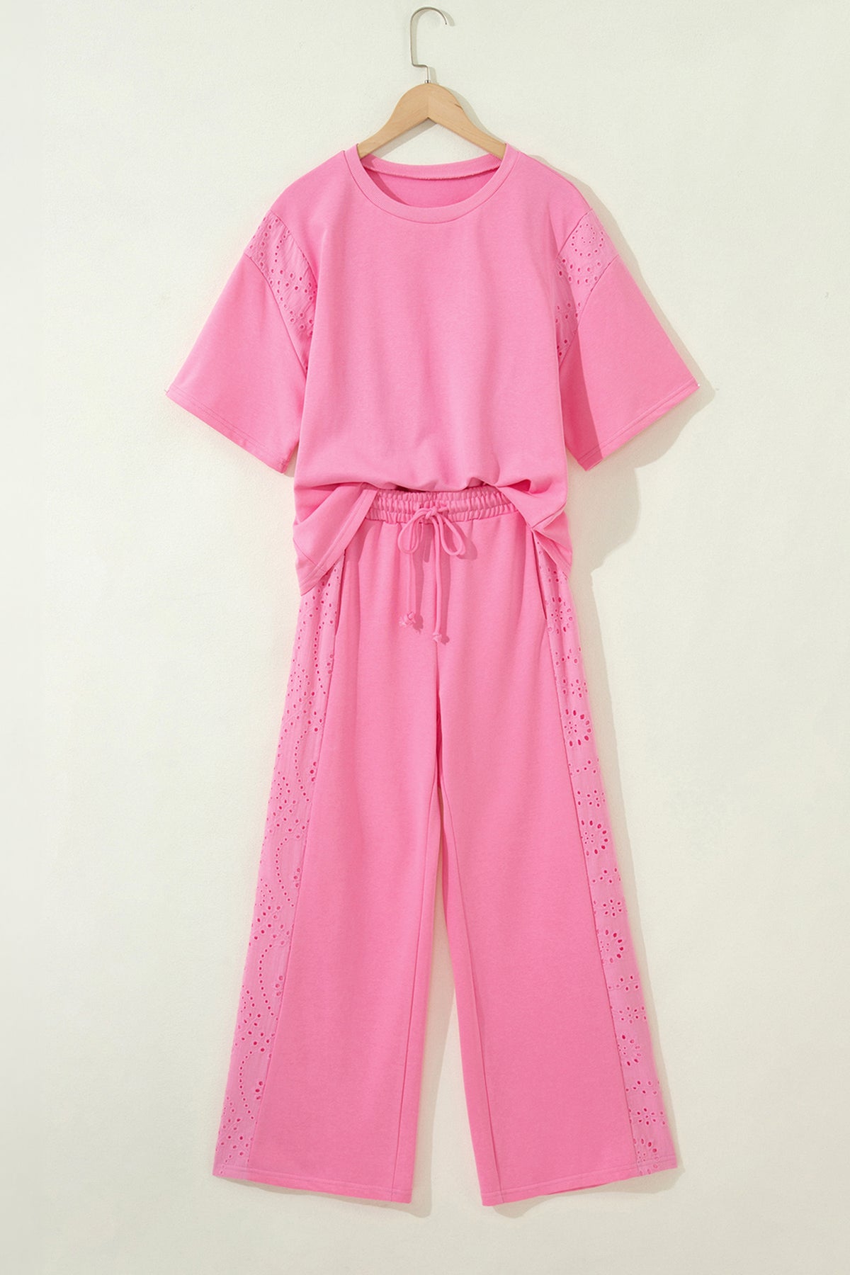 Pink outfit with a top and pants on a hanger against a white background front view