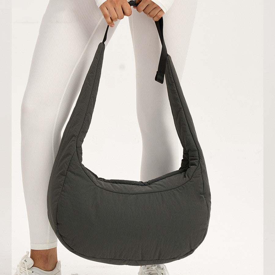 Person holding a gray shoulder bag against a white background