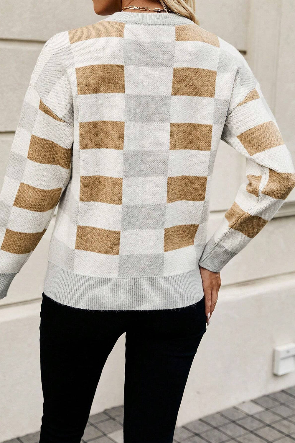 Person wearing a checkered sweater with brown and white stripes.