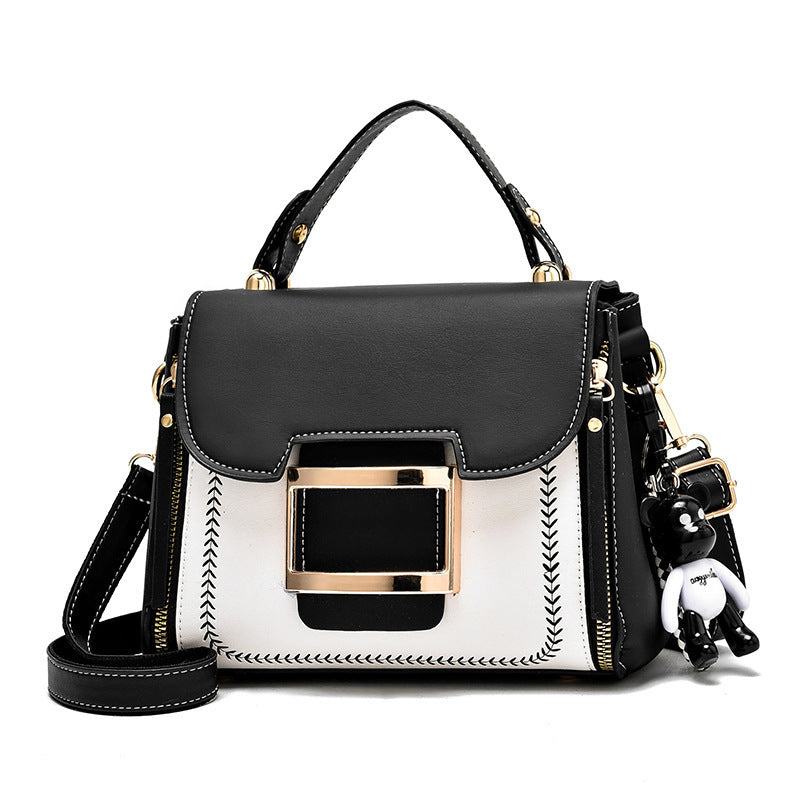 Black and white handbag with gold accents on a white background