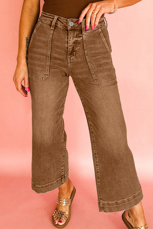 Brown wide-leg jeans worn by a person on a pink background