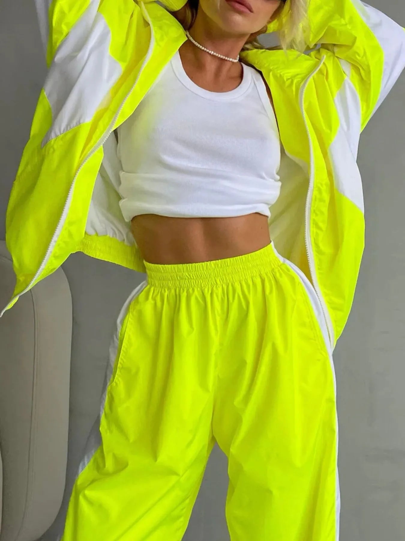 Person wearing a bright yellow tracksuit with white accents on a plain background
