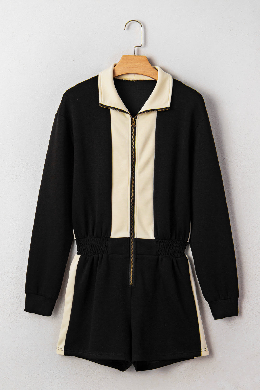 Black and beige jumpsuit on a hanger against a white background