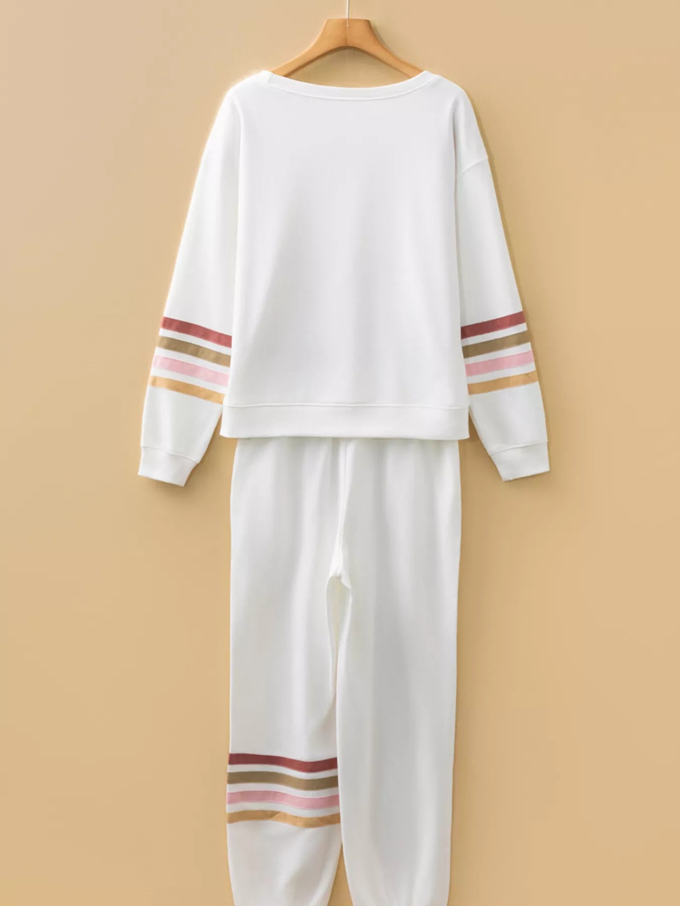 White sweatshirt and pants set with colorful stripes on a beige background