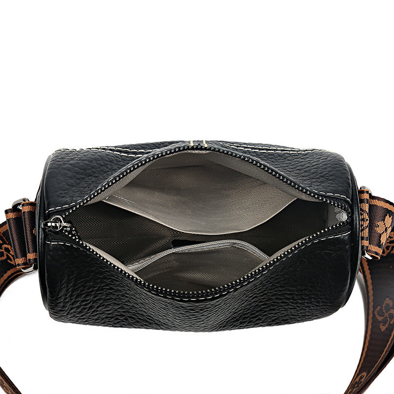 Black leather crossbody bag with brown strap on a white background