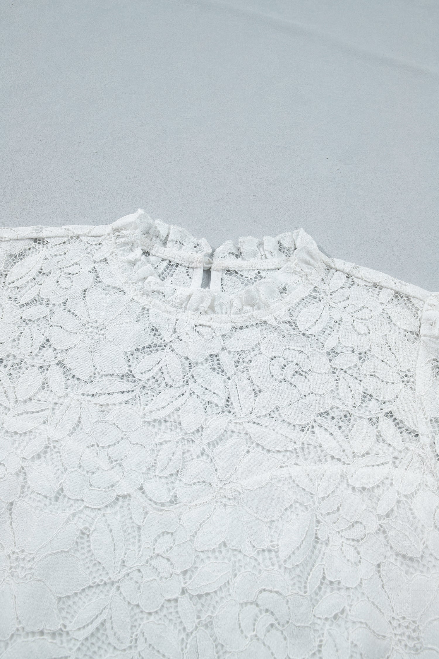 White lace top on a light gray background detailed view