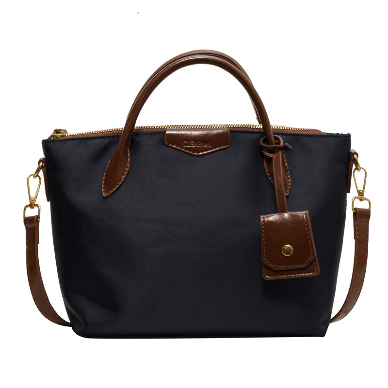 Black handbag with brown leather accents on a white background
