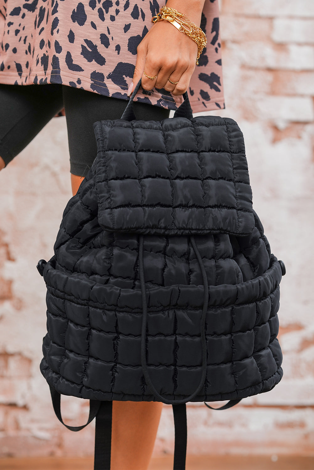 Model holding a Chic black Quilted Puffer Flap Backpack 