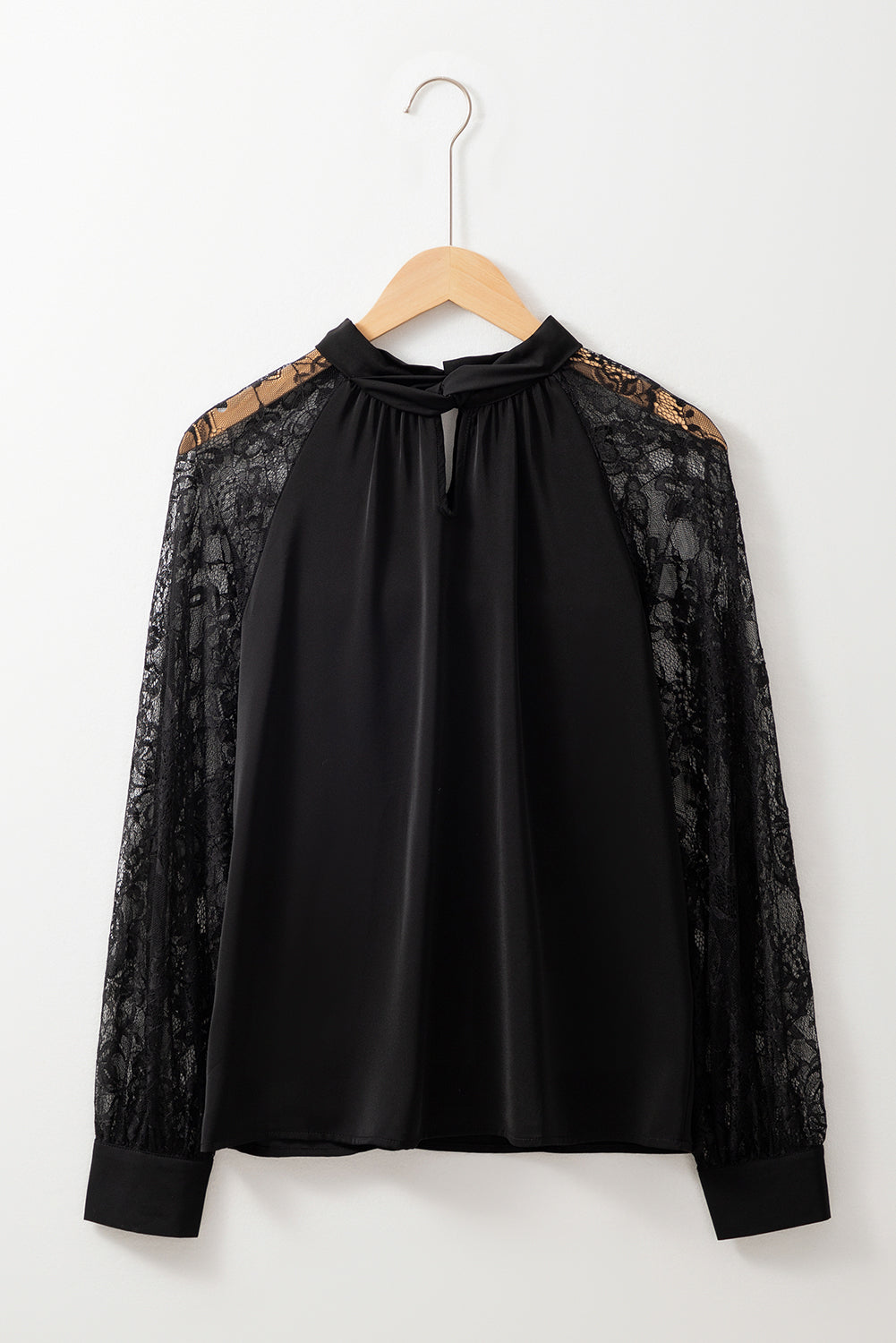 Black blouse with lace sleeves on a wooden hanger against a white background