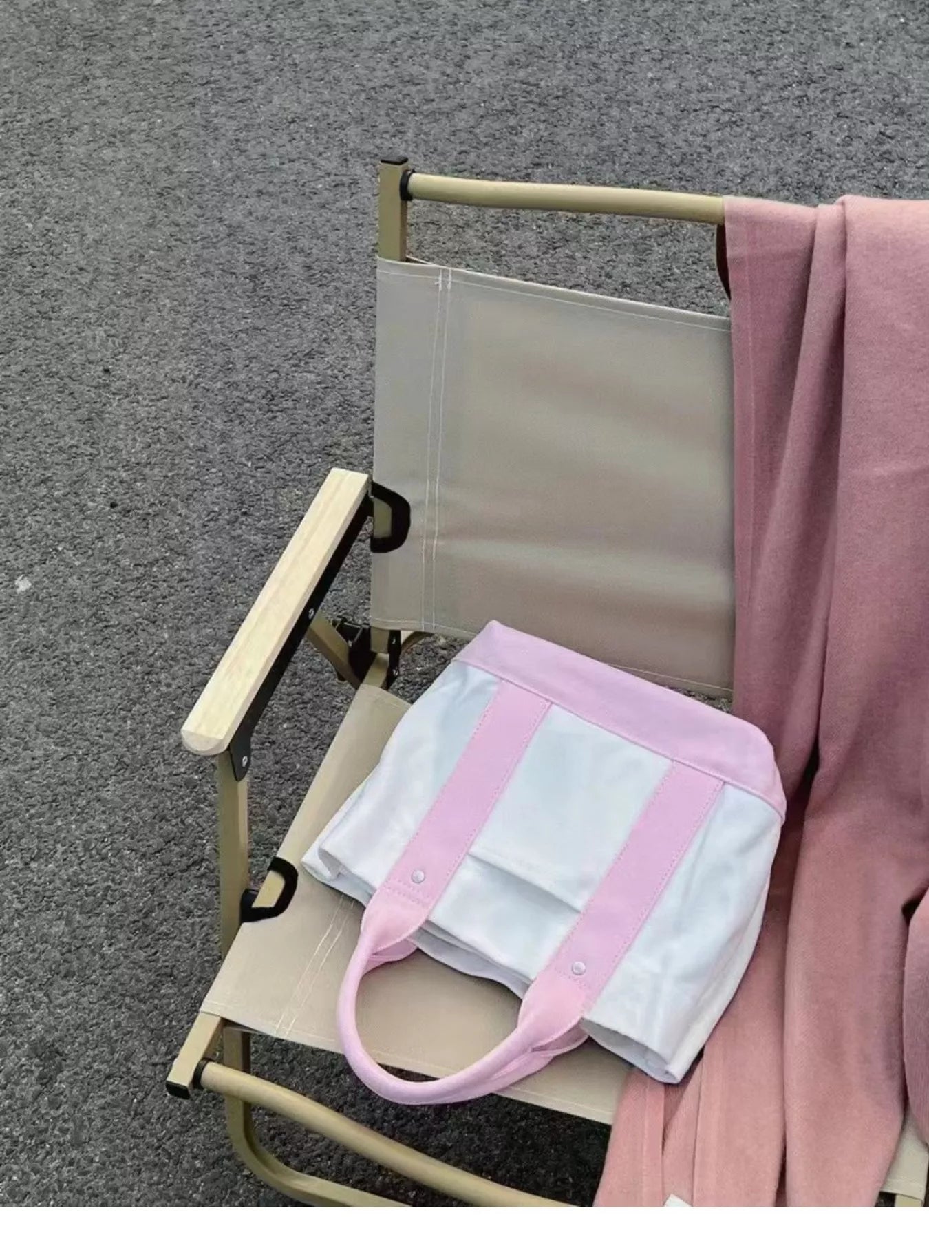 Pink and white bag on a folding chair with a pink garment draped over it on a gray surface.