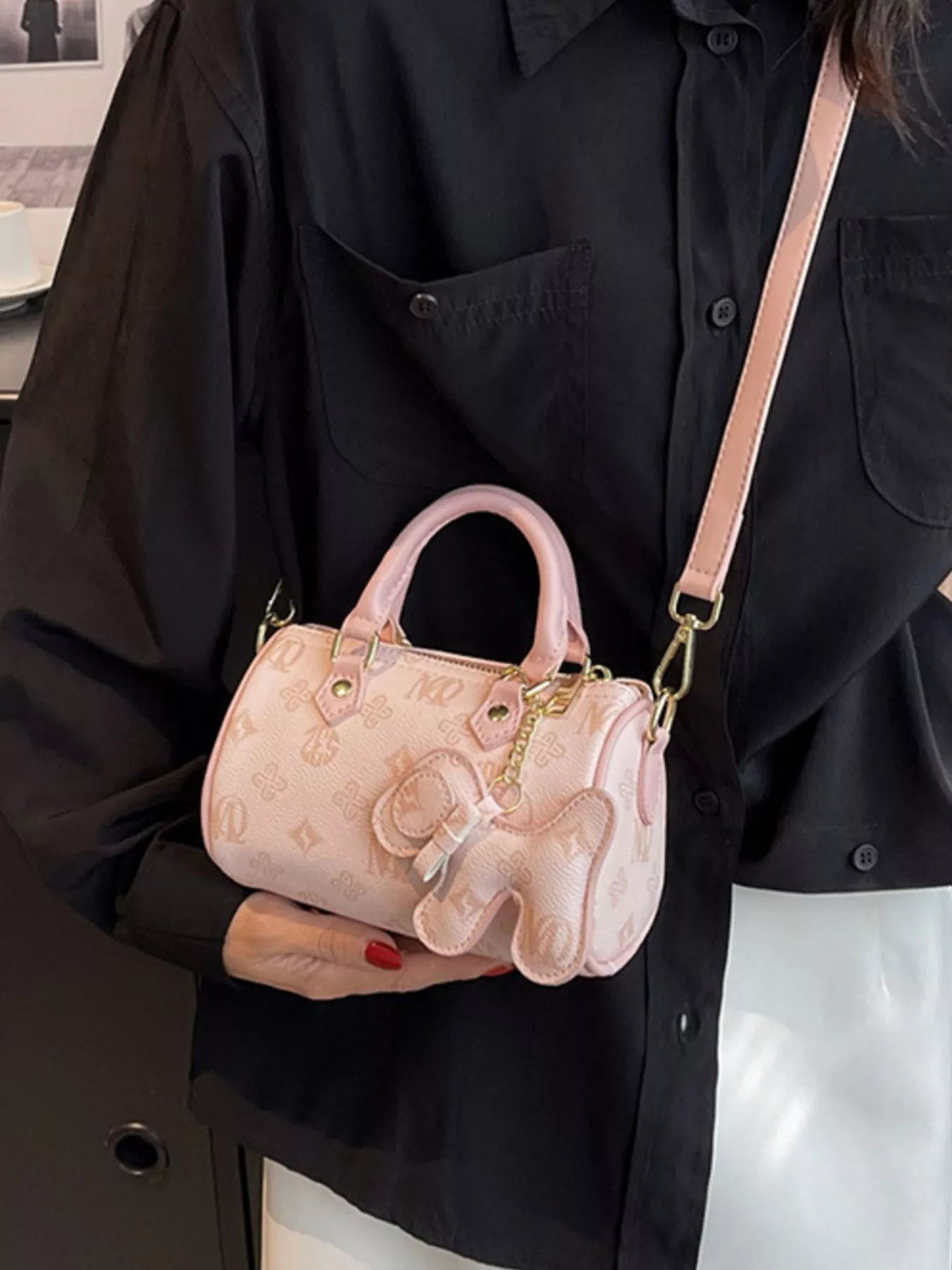Person holding a pink handbag with a character design against a black background
