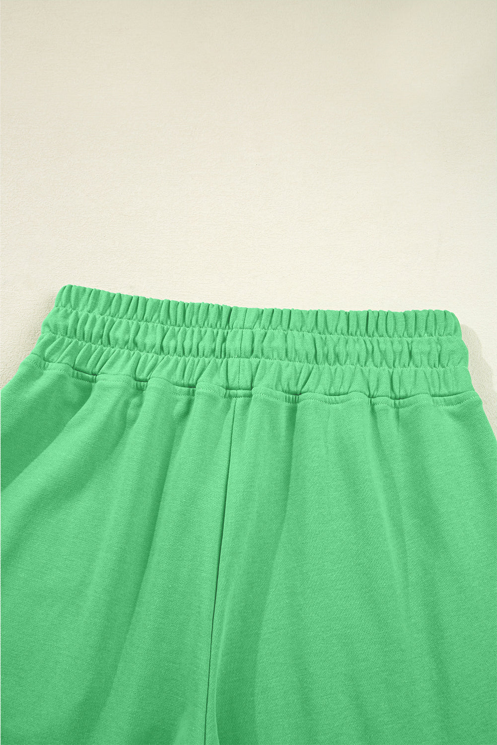 Green pants with an elastic waistband on a beige background