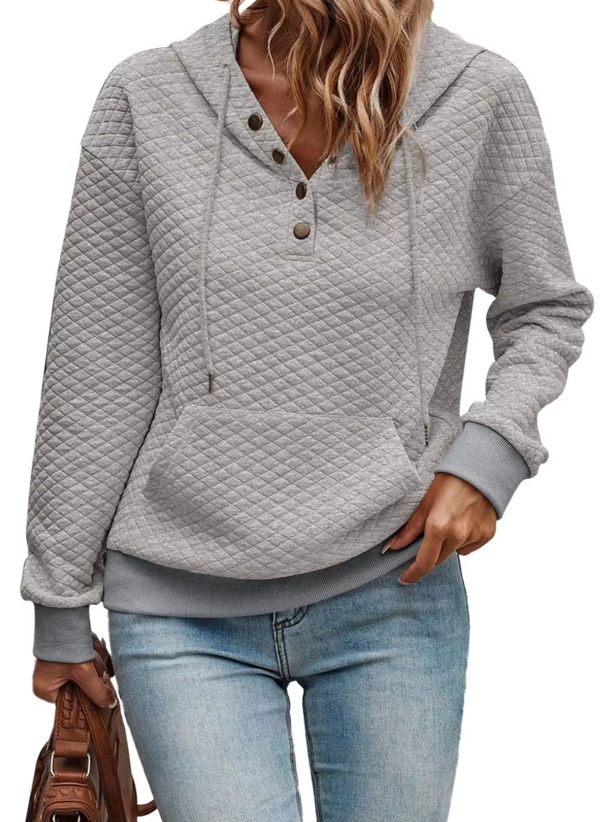 Person wearing a gray quilted hoodie and blue jeans on a white background