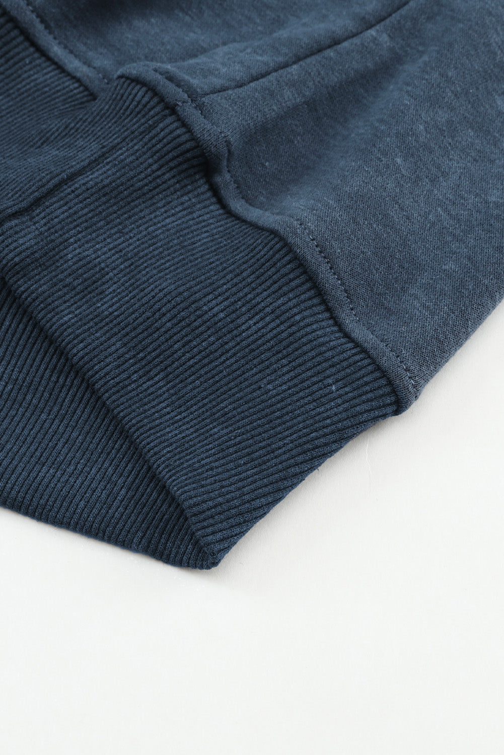 Close-up of a dark blue sweater sleeve on a light background