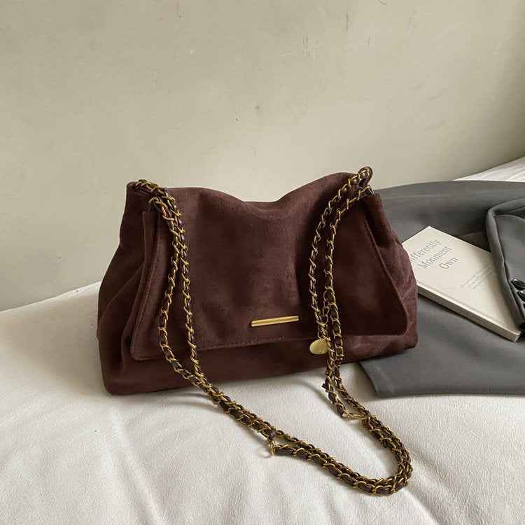 Brown handbag with gold chain strap on a light surface